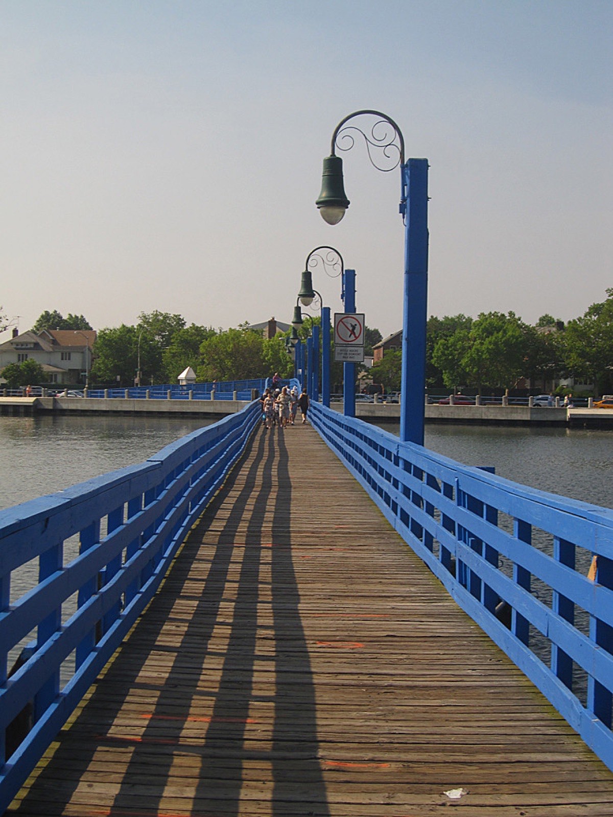 A blue wooden footbridge over the water in Sheepshead Bay